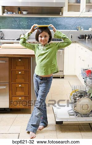 Girl balancing plate on head in kitchen View Large Photo Image Stock Image - Girl balancing plate on head in kitchen. Fotosearch