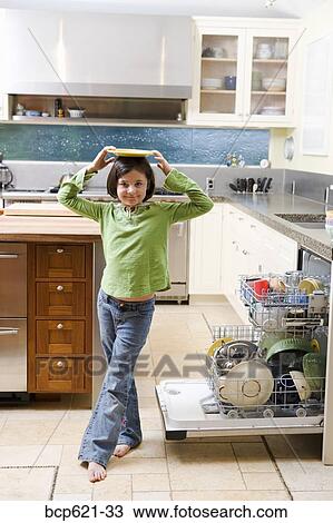 Girl balancing plate on head in kitchen View Large Photo Image Stock Image - Girl balancing plate on head in kitchen. Fotosearch