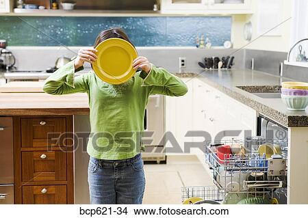 Girl in kitchen with plate hiding face View Large Photo Image Picture - Girl in kitchen with plate hiding face. Fotosearch