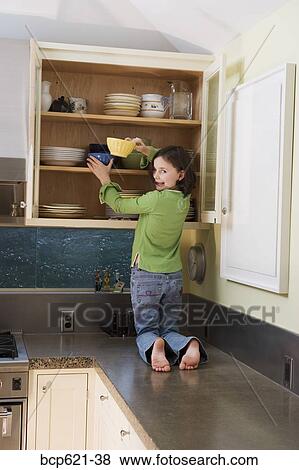 Girl kneeling on kitchen counter getting bowl View Large Photo Image Stock Photo - Girl kneeling on kitchen counter getting bowl. Fotosearch