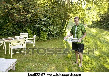 Man carrying tray to table in yard View Large Photo Image Stock Photo - Man carrying tray to table in yard. Fotosearch