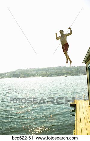 Man jumping into water from houseboat roof View Large Photo Image Stock Image - Man jumping into water from houseboat roof. Fotosearch