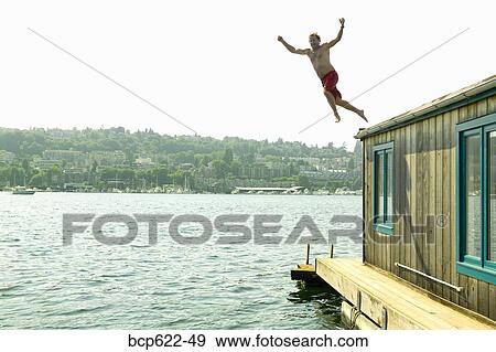 Man jumping into water from houseboat roof View Large Photo Image Stock Photo - Man jumping into water from houseboat roof. Fotosearch