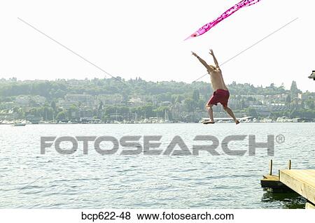 Man jumping into water with kite View Large Photo Image Stock Photo - Man jumping into water with kite. Fotosearch