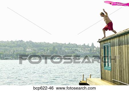 Man on roof of houseboat with kite View Large Photo Image Stock Photograph - Man on roof of houseboat with kite. Fotosearch