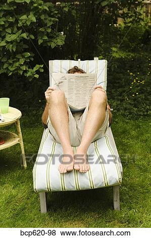 Man reading newspaper on chair in yard View Large Photo Image Stock Photo - Man reading newspaper on chair in yard. Fotosearch