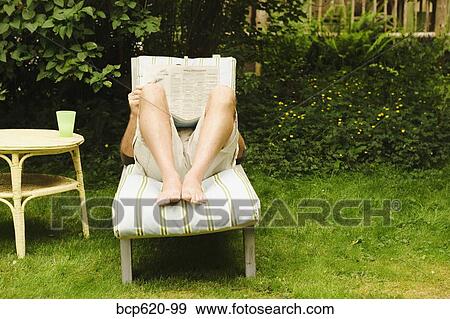 Man reading newspaper on chair in yard View Large Photo Image Stock Photo - Man reading newspaper on chair in yard. Fotosearch