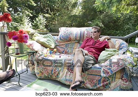 Man relaxing on couch on porch View Large Photo Image Stock Image - Man relaxing on couch on porch. Fotosearch