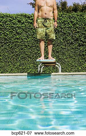 Man standing on swimming pool diving board View Large Photo Image Stock Photo - Man standing on swimming pool diving board. Fotosearch
