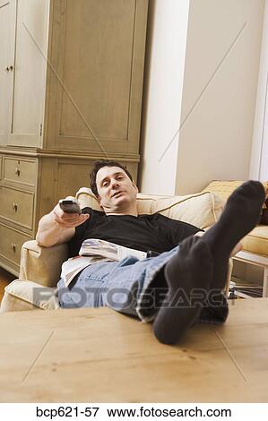 Stock Photo - Man with remote control relaxing at home. Fotosearch