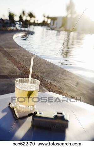Stock Photo - Margarita and camera on poolside table. Fotosearch