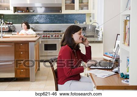 Mother using phone and computer in kitchen View Large Photo Image Stock Photograph - Mother using phone and computer in kitchen. Fotosearch