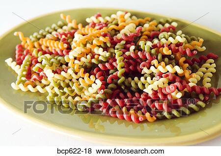 Stock Photo - Plate of multicolored curly dry pasta. Fotosearch