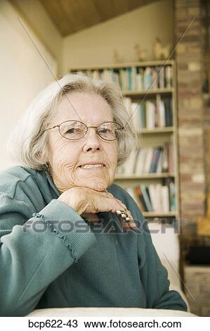 Stock Image - Portrait of elderly woman seated inside. Fotosearch
