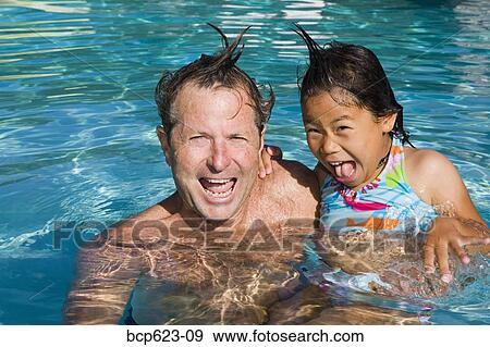 Stock Photo - Portrait of father and daughter being silly in pool. Fotosearch
