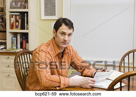 Stock Photo - Portrait of man doing paperwork at home. Fotosearch