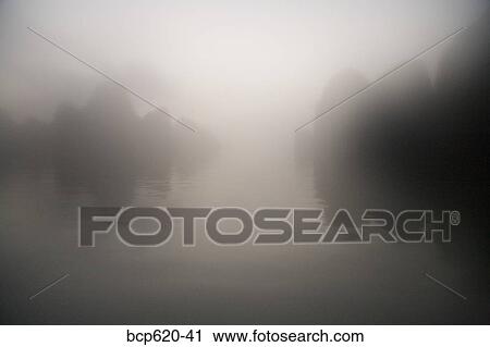 Rocks and water through mist at dawn View Large Photo Image Stock Image - Rocks and water through mist at dawn. Fotosearch
