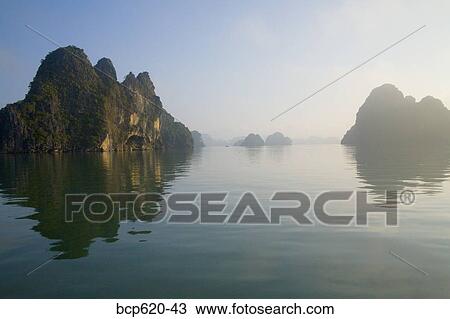 Stock Image - Rocky islands with still water in misty morning. Fotosearch