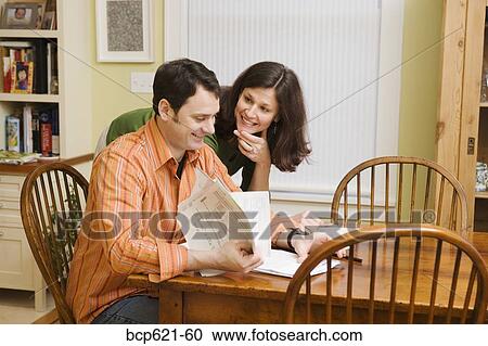 Stock Image - Smiling couple doing paperwork at home. Fotosearch