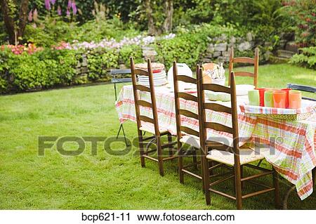 Stock Image - Table and chairs on lawn in garden. Fotosearch