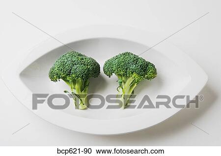 Two broccoli crowns in a dish View Large Photo Image Stock Image - Two broccoli crowns in a dish. Fotosearch