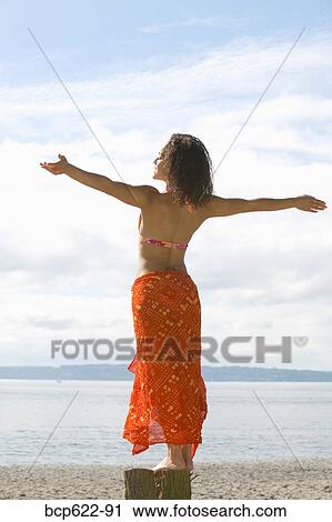 Stock Image - Woman basking in sun on beach. Fotosearch