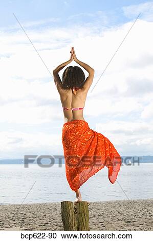 Stock Image - Woman in yoga pose on beach. Fotosearch