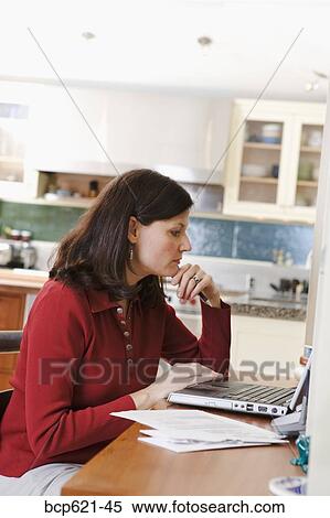 Woman using laptop computer in kitchen View Large Photo Image Stock Photography - Woman using laptop computer in kitchen. Fotosearch