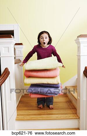 Young girl dropping pile of towels on stairs View Large Photo Image Stock Photograph - Young girl dropping pile of towels on stairs. Fotosearch