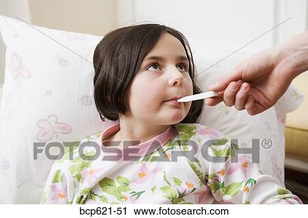 Stock Image - Young girl having temperature taken. Fotosearch
