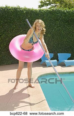 Young woman poolside with pink floatation device View Large Photo Image Stock Photo - Young woman poolside with pink floatation device. Fotosearch