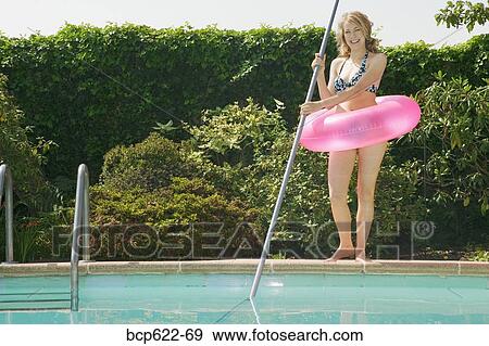 Young woman poolside with pink floatation device View Large Photo Image Stock Photo - Young woman poolside with pink floatation device. Fotosearch