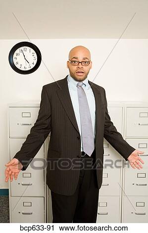 Stock Image - balding, eyeglasses, clock, businessman, african ethnicity. Fotosearch