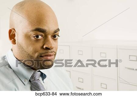 Picture - balding, file cabinet, close up, businessman, african ethnicity. Fotosearch