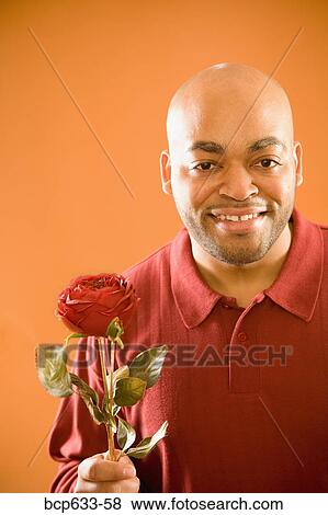 Stock Photo - balding, head & shoulders, fortysomething, flower, african ethnicity. Fotosearch