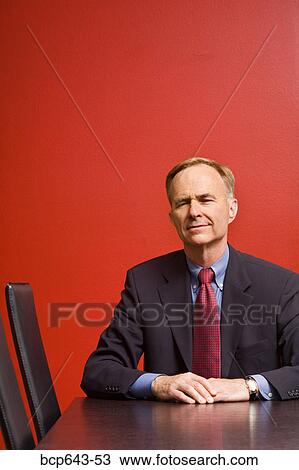 Stock Image - Businessman sitting at conference table. Fotosearch