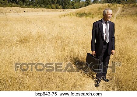 Businessman standing in field View Large Photo Image Stock Photography - Businessman standing in field. Fotosearch