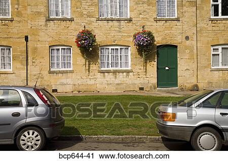 Stock Image - Cars parked outside stone cottages, Gloucestershire, United Kingdom. Fotosearch