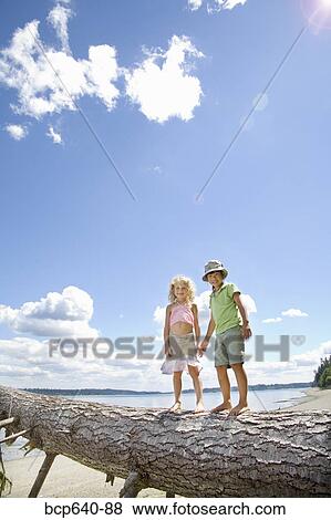 Stock Photo - Children balancing on fallen tree. Fotosearch