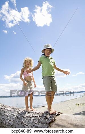 Stock Photo - Children balancing on fallen tree. Fotosearch