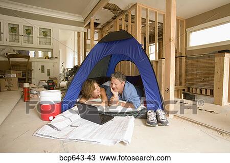 Couple camping in their unfinished living room View Large Photo Image Stock Image - Couple camping in their unfinished living room. Fotosearch