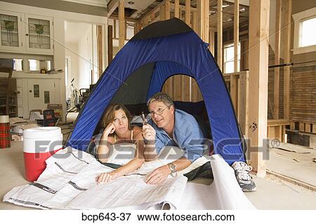 Couple camping in their unfinished living room View Large Photo Image Stock Photo - Couple camping in their unfinished living room. Fotosearch