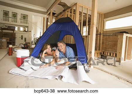Couple camping in their unfinished living room View Large Photo Image Stock Photo - Couple camping in their unfinished living room. Fotosearch