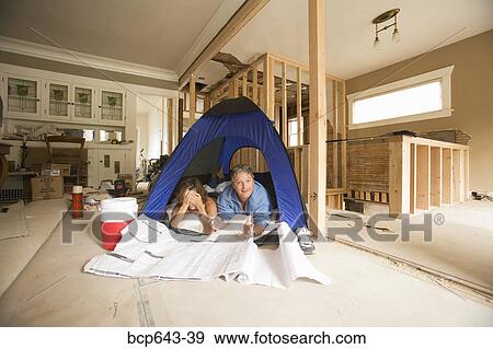 Couple camping in their unfinished living room View Large Photo Image Stock Photo - Couple camping in their unfinished living room. Fotosearch