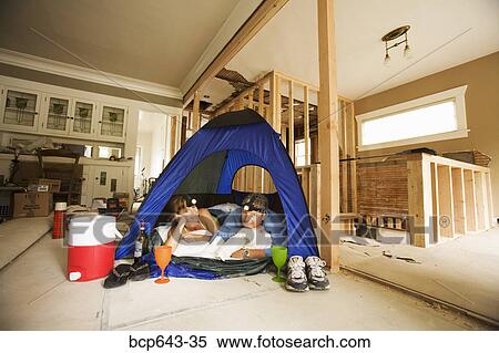 Stock Photography - Couple camping in their unfinished living room. Fotosearch