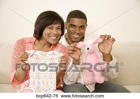 Couple displaying baby clothes View Large Photo Image Stock Photography - Couple displaying baby clothes . Fotosearch