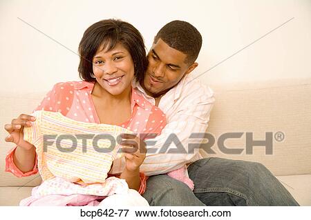 Couple examining baby clothes View Large Photo Image Stock Photo - Couple examining baby clothes. Fotosearch