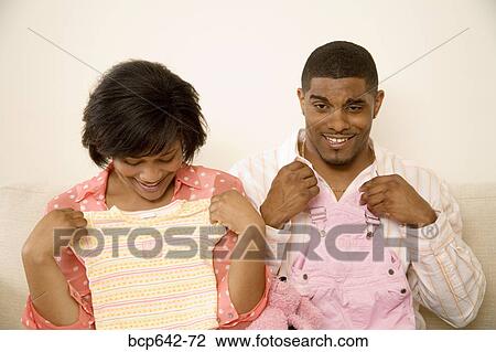 Couple holding baby clothes against themselves View Large Photo Image Stock Image - Couple holding baby clothes against themselves. Fotosearch