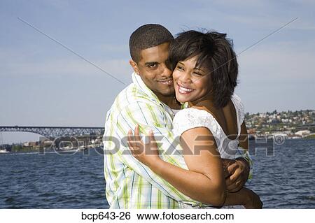 Stock Photograph - Couple hugging by bay. Fotosearch