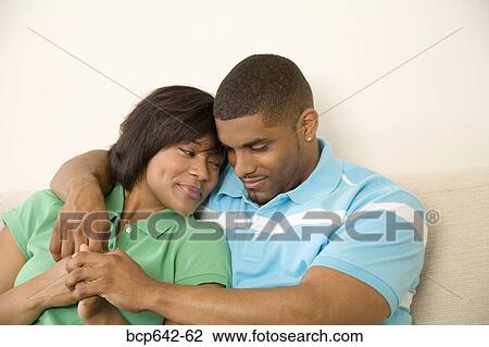 Stock Image - Couple hugging on a couch. Fotosearch